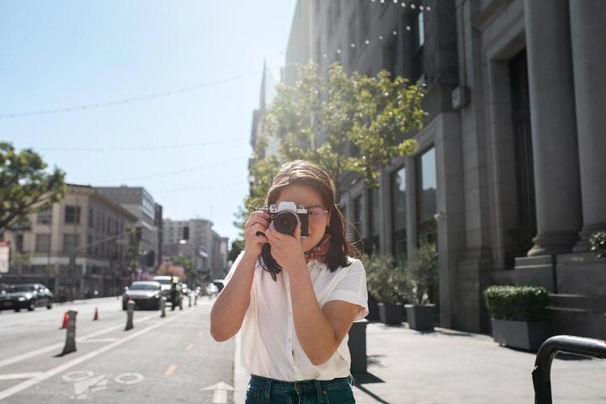 a woman taking a picture with a camera on a city street