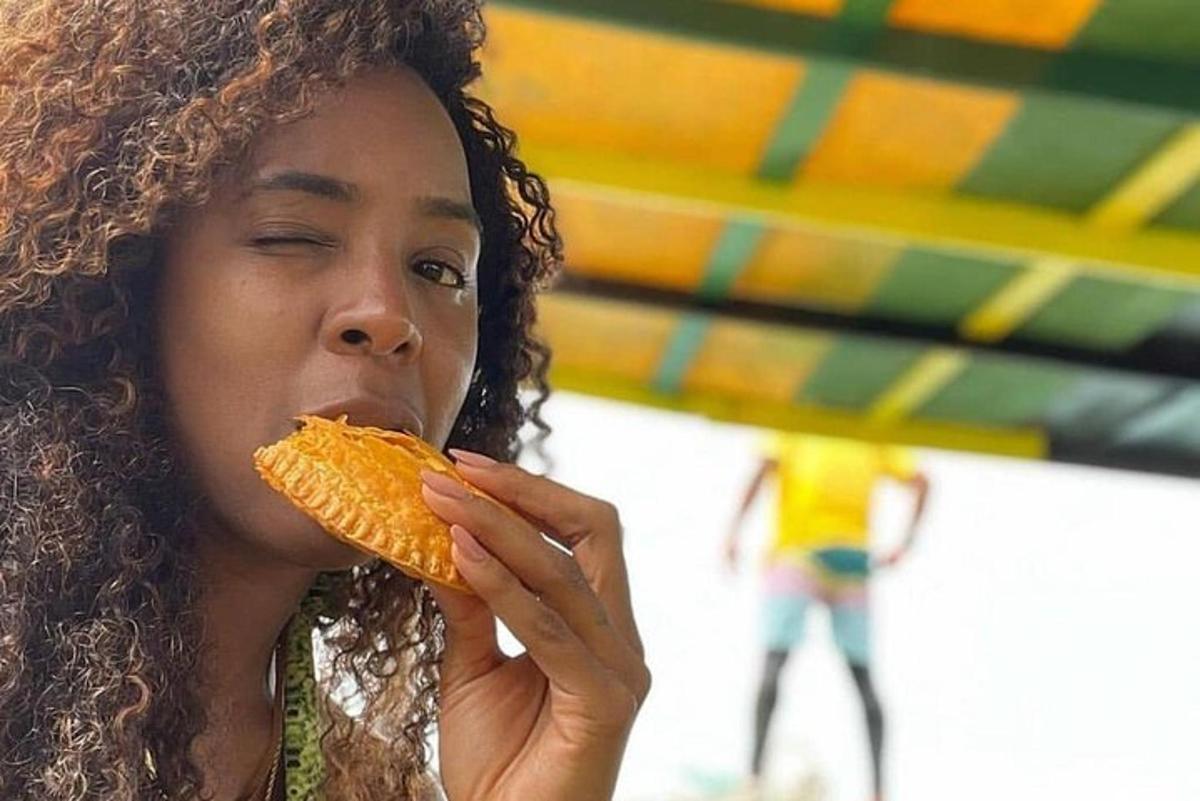 uma mulher comendo um cachorro-quente na praia