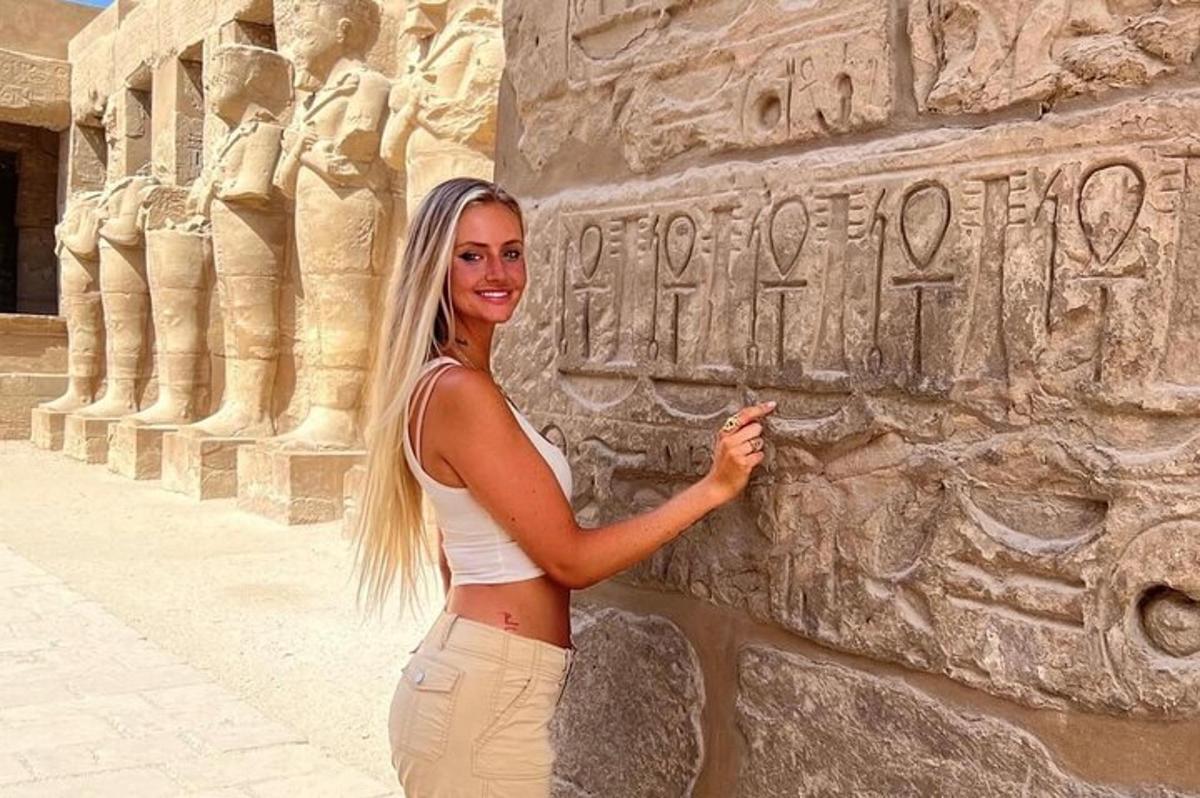 a woman is standing next to a stone wall