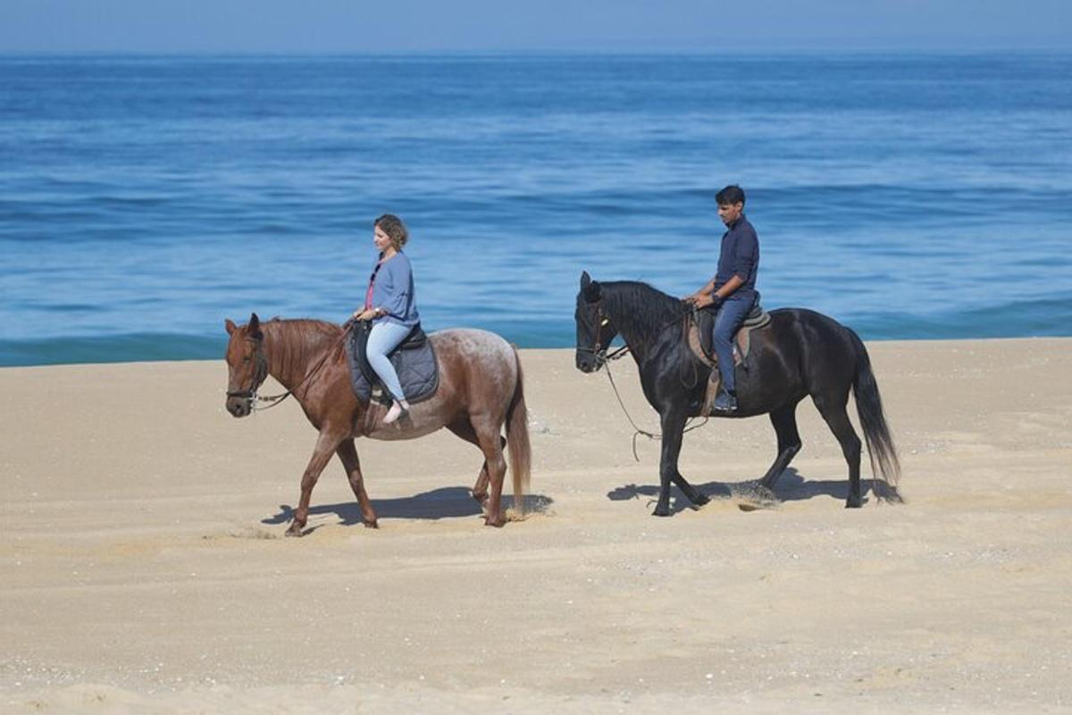 un home i una dona muntant a cavall a la platja
