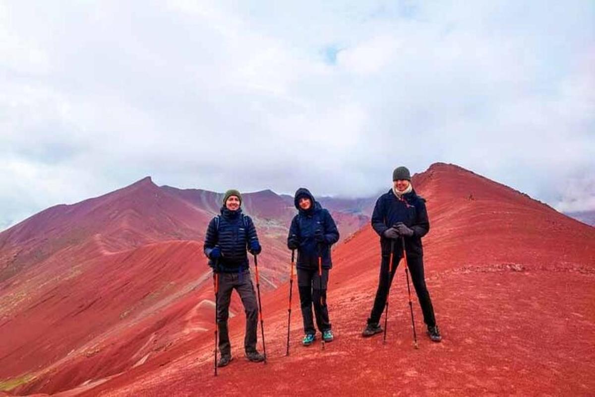 tre persone in piedi sulla cima di una montagna rossa