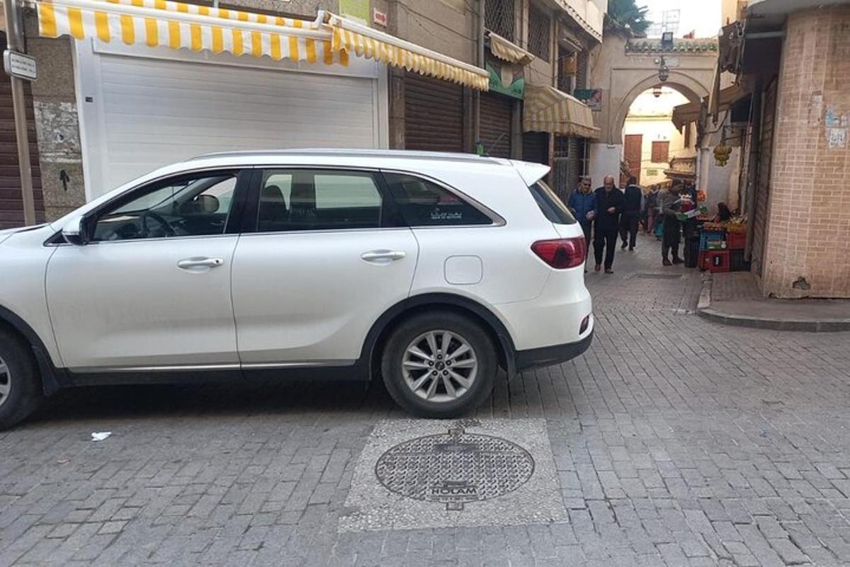 bílé auto zaparkované na ulici vedle mužské díry