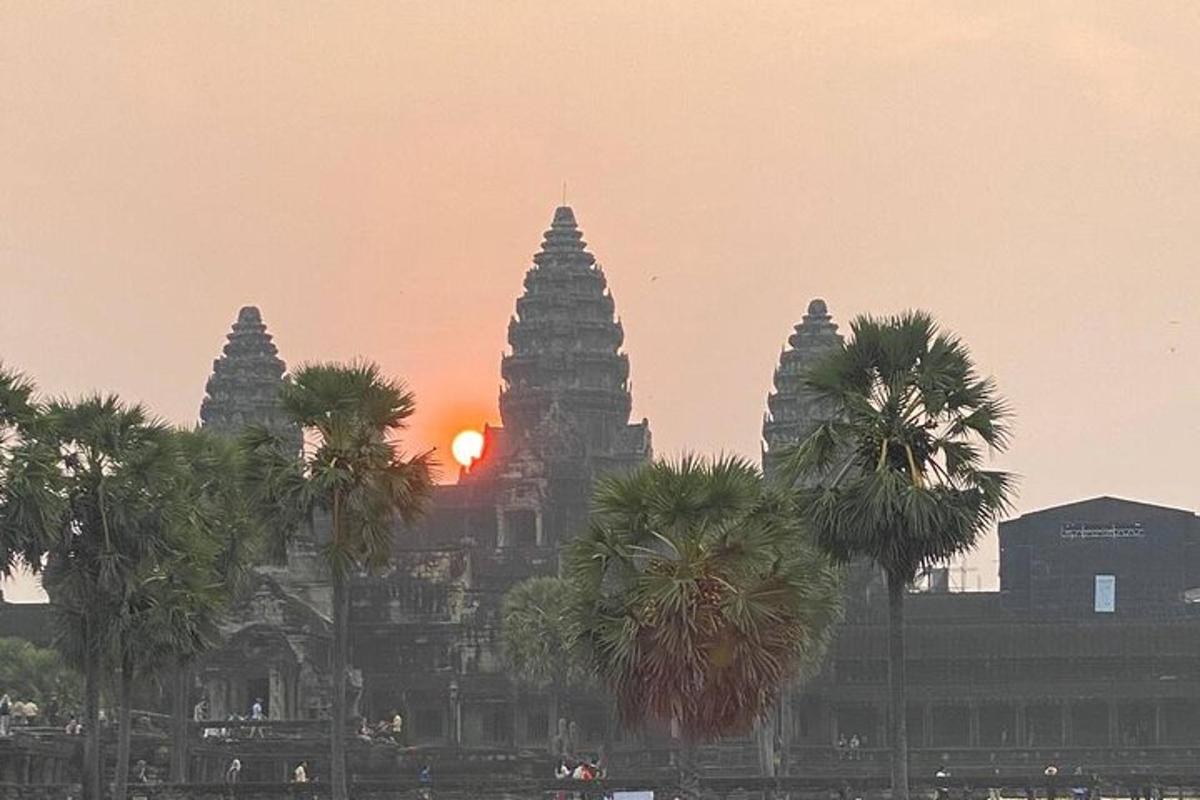 Un edificio con una puesta de sol al fondo con palmeras.