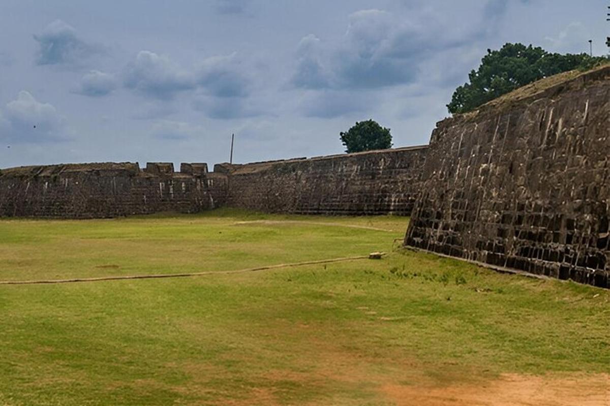 Un gran muro de piedra con un campo de hierba al lado.
