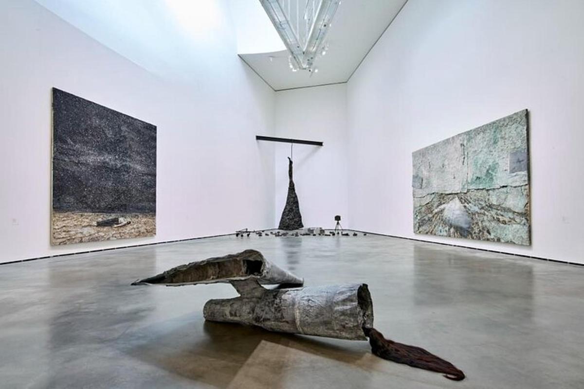 a sculpture in a white room with three paintings