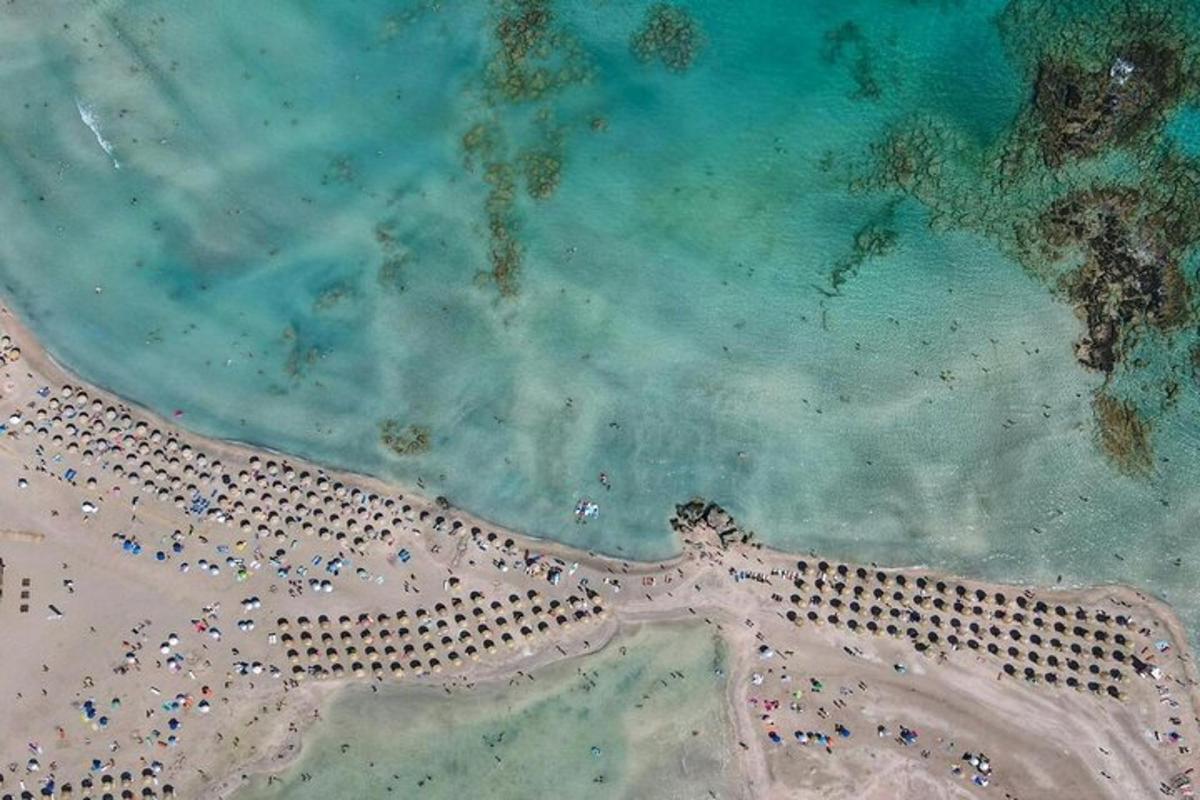 una vista dall'alto di una spiaggia con persone e un faro