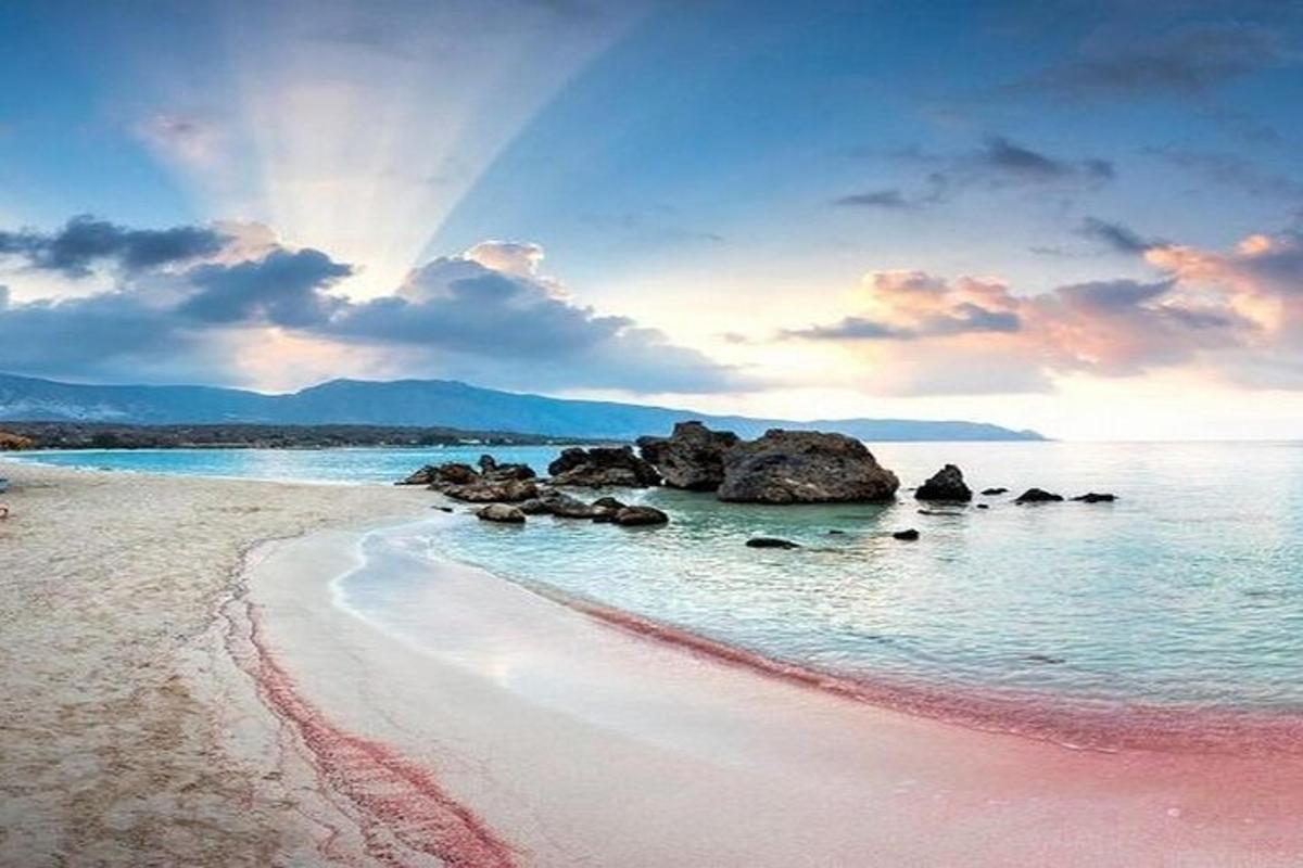 una spiaggia con rocce nell'acqua con un arcobaleno