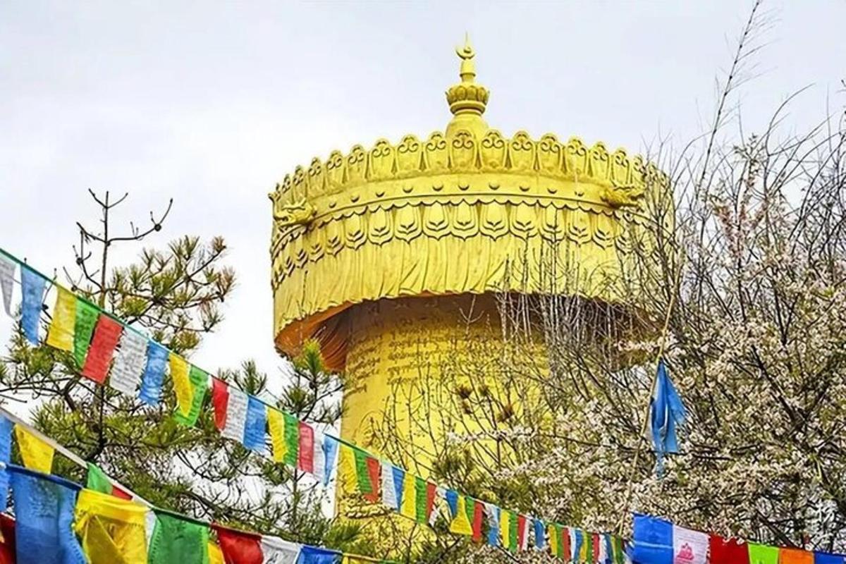 a yellow tower with prayer flags in front of it