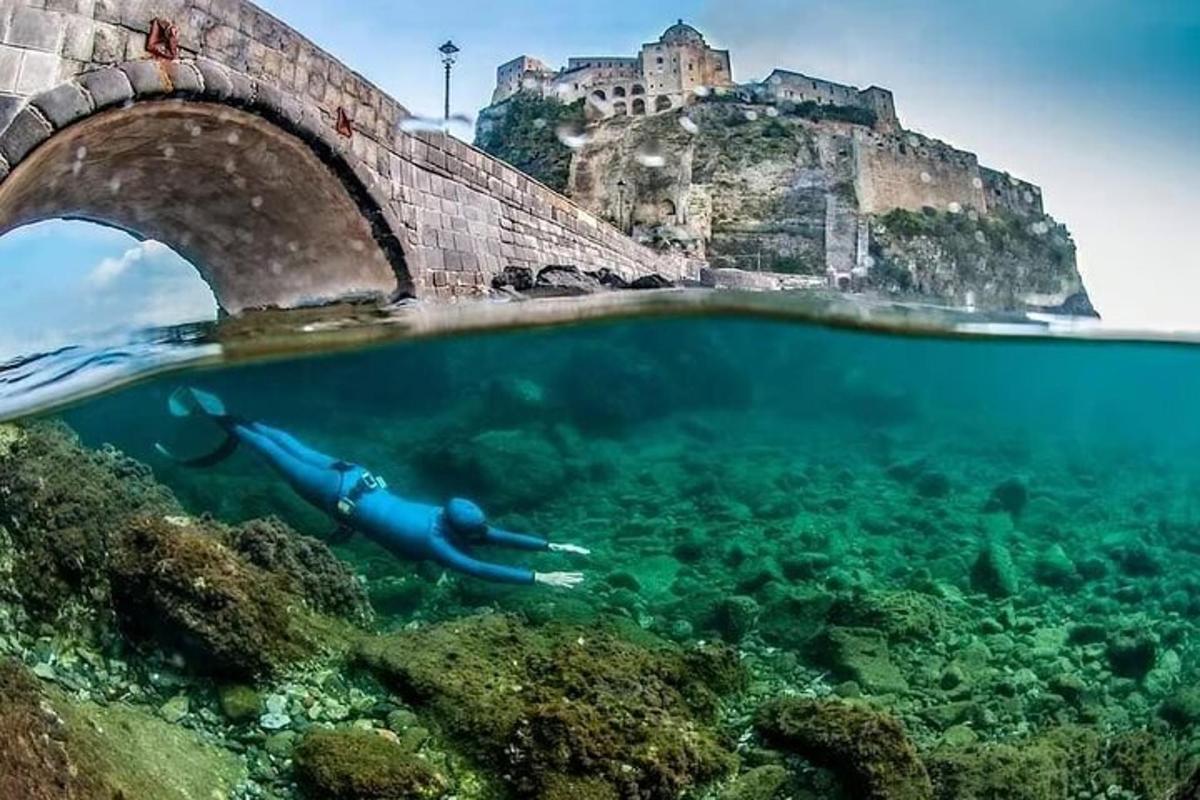 a person swimming in the ocean under a bridge