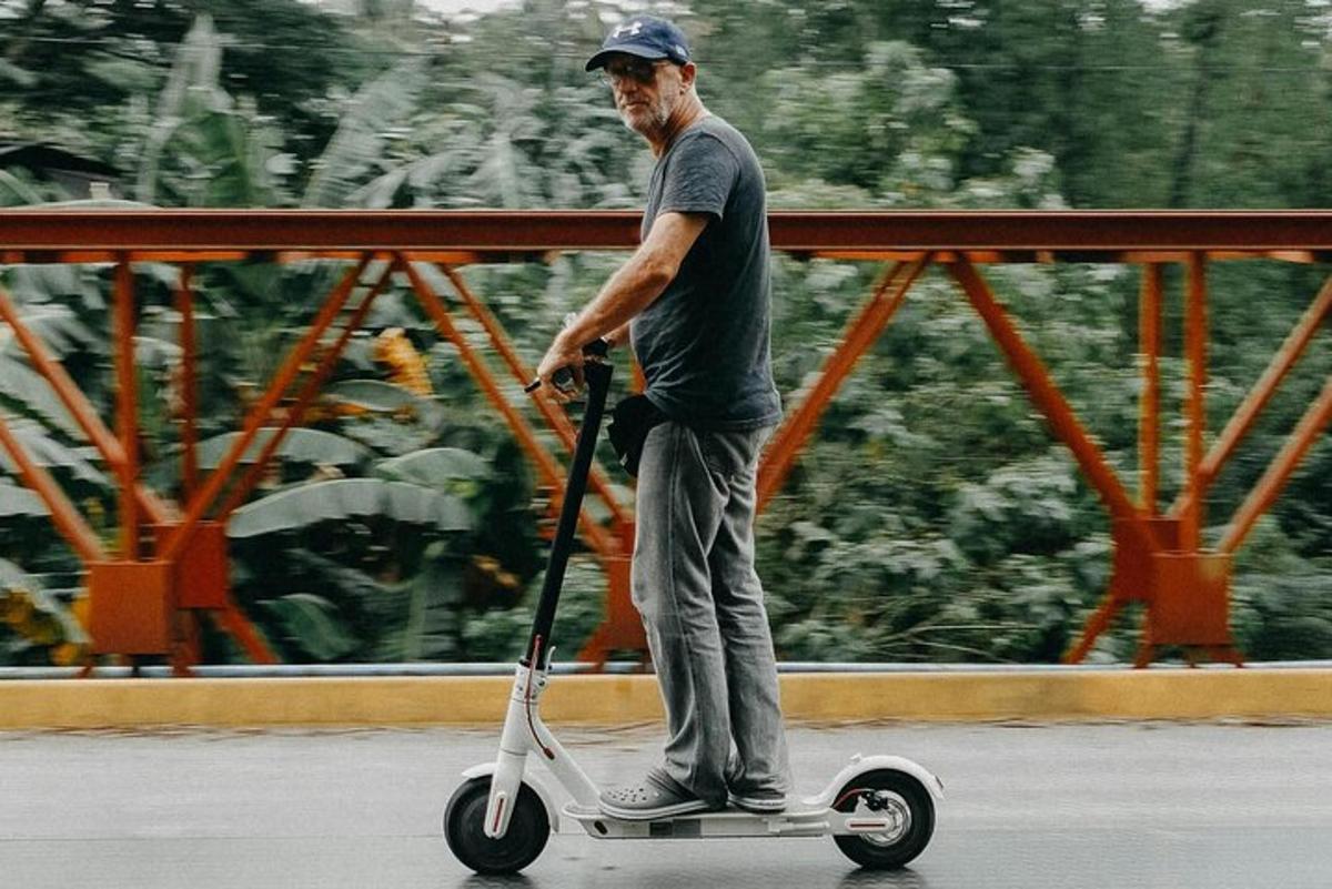 seorang lelaki tua menunggang skuter di jalan