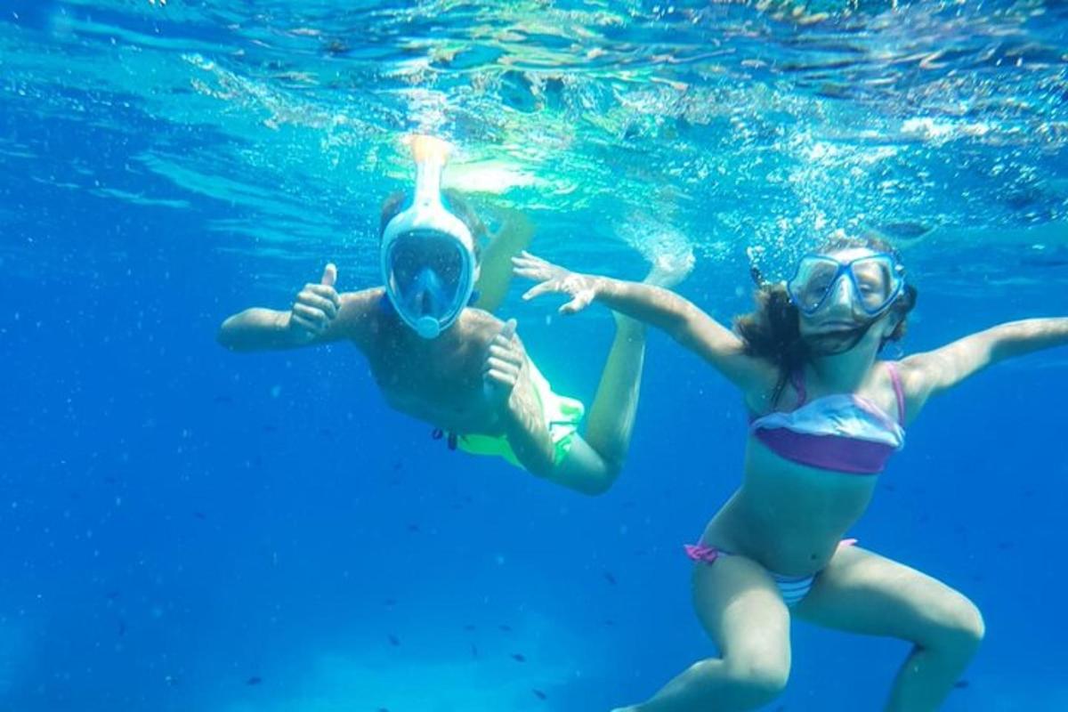 Dos personas están nadando en el agua azul.