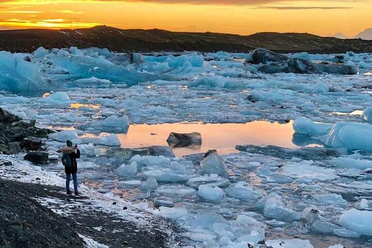 maður stendur á strönd með ísjökum