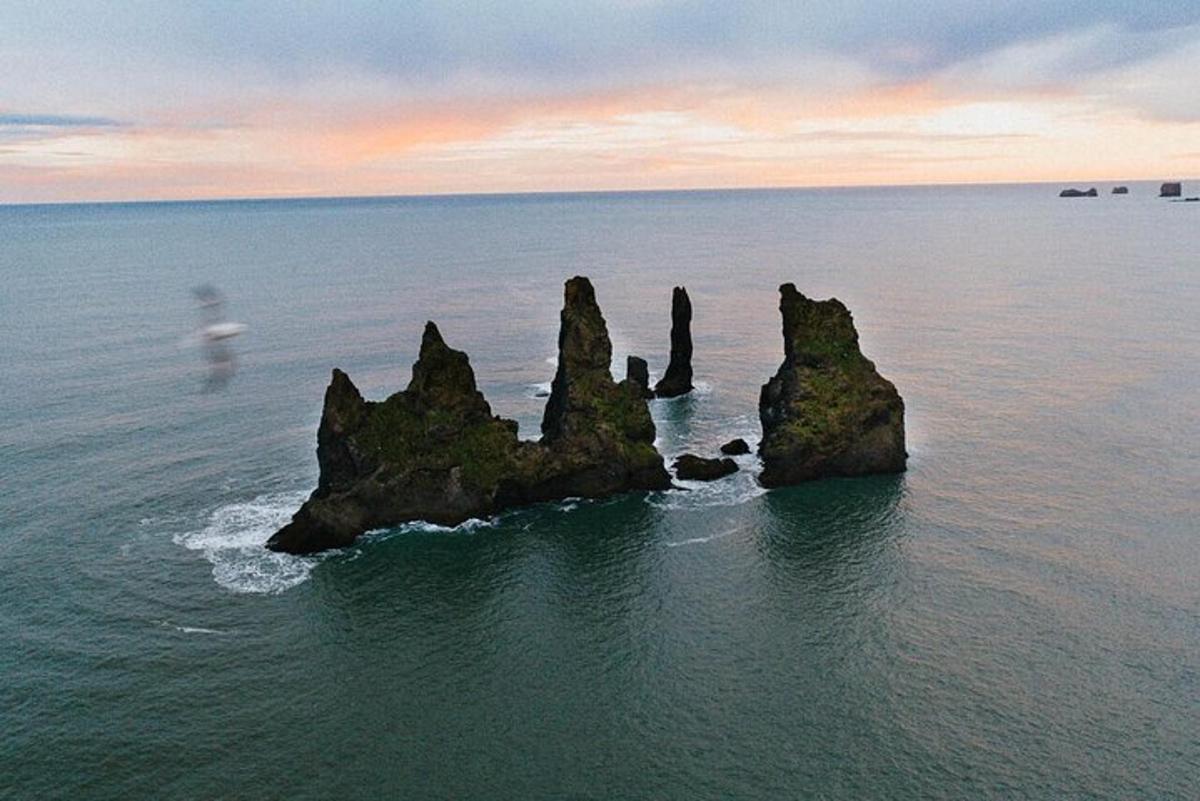 a group of rocks in the water at sunset