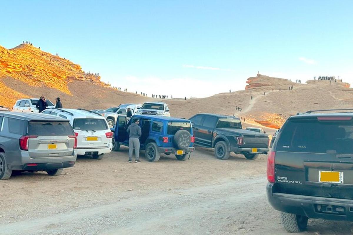a group of cars parked on the side of a dirt road