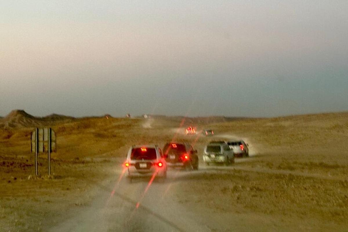 een groep auto's die over een onverharde weg rijden