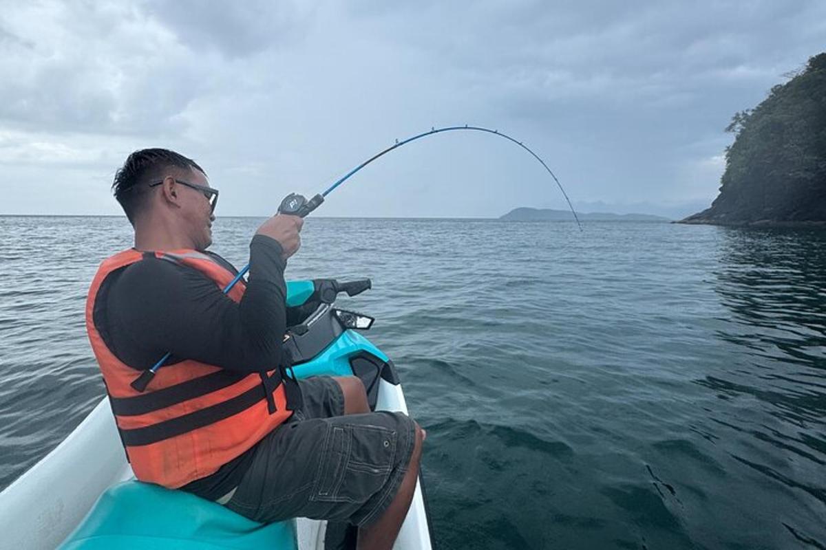 seorang lelaki yang duduk di atas bot memancing di atas air