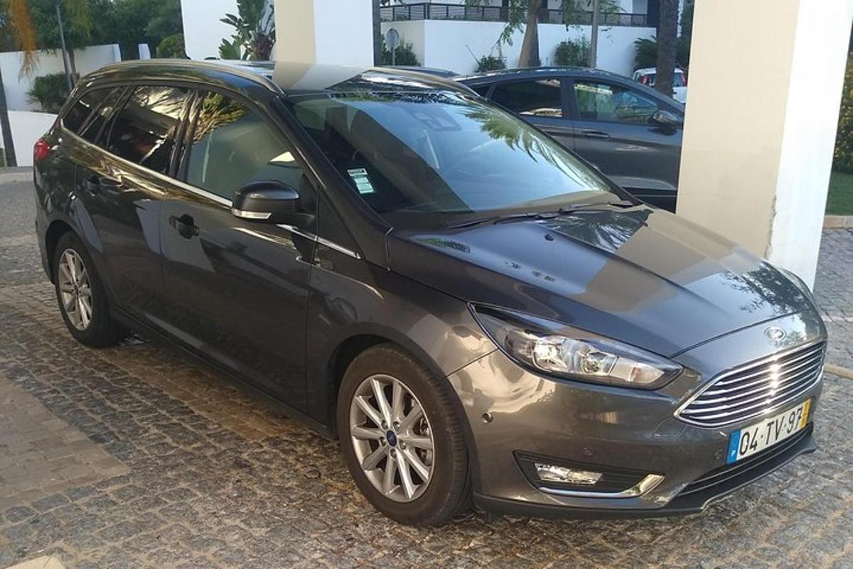 um carro preto estacionado ao lado de um prédio