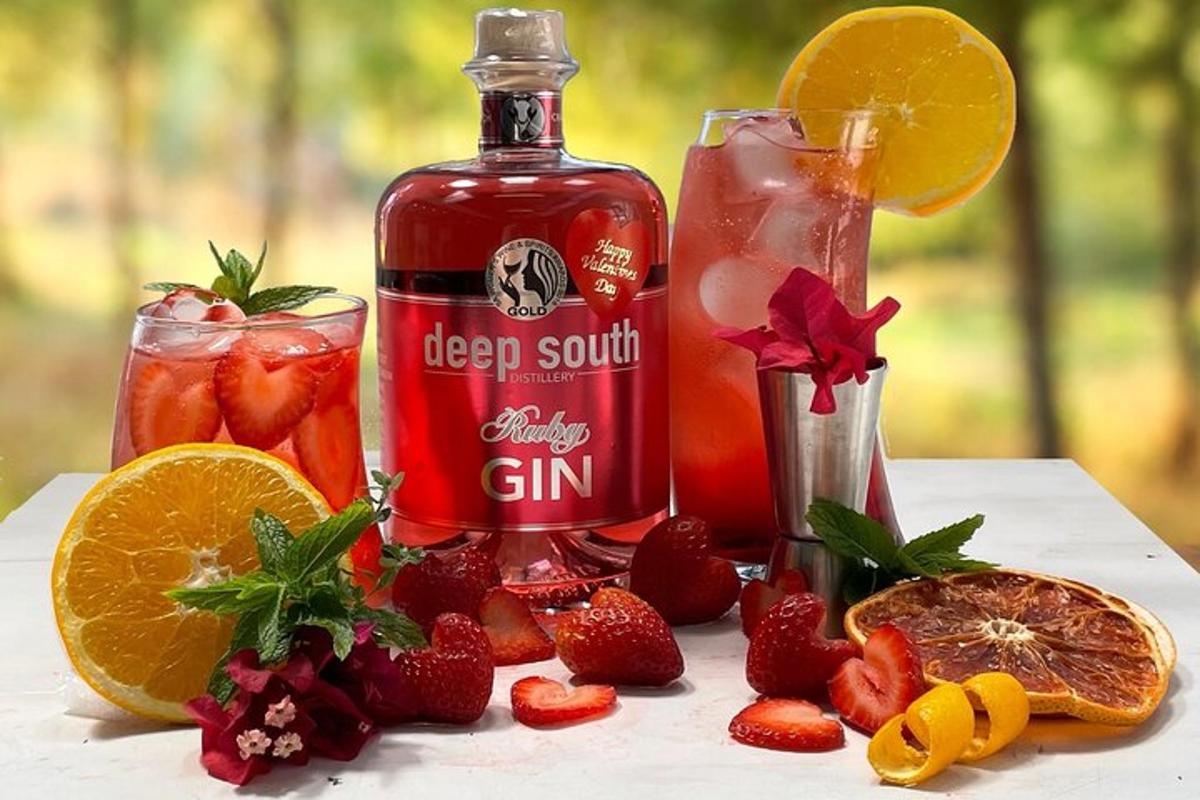 eine Flasche roten Sirup und zwei Gläser Erdbeeren