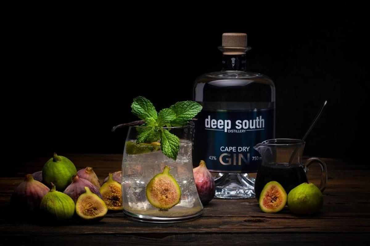 sebotol gin duduk di sebelah sekumpulan buah delima