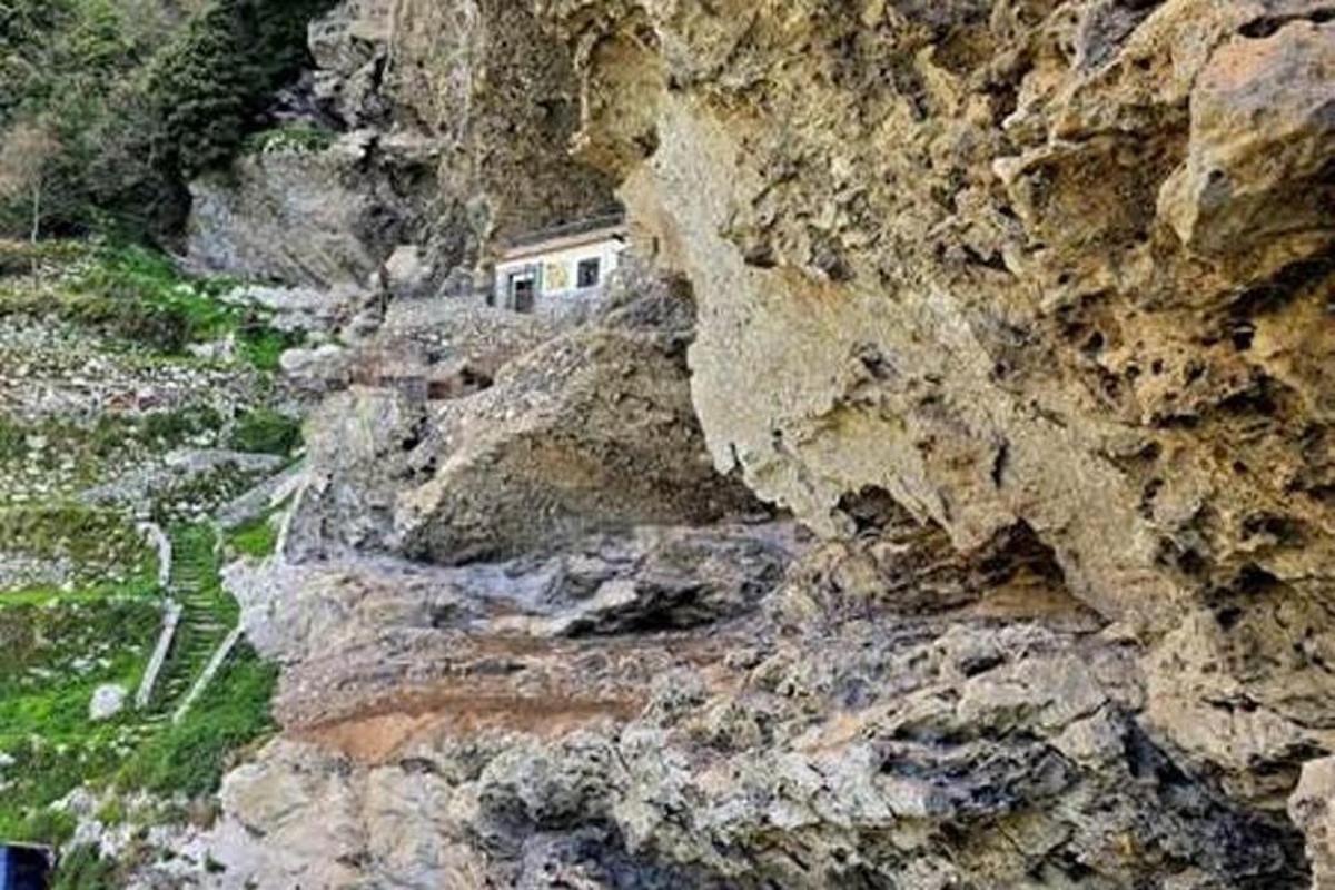 ein felsiger Berg mit einem Haus darauf
