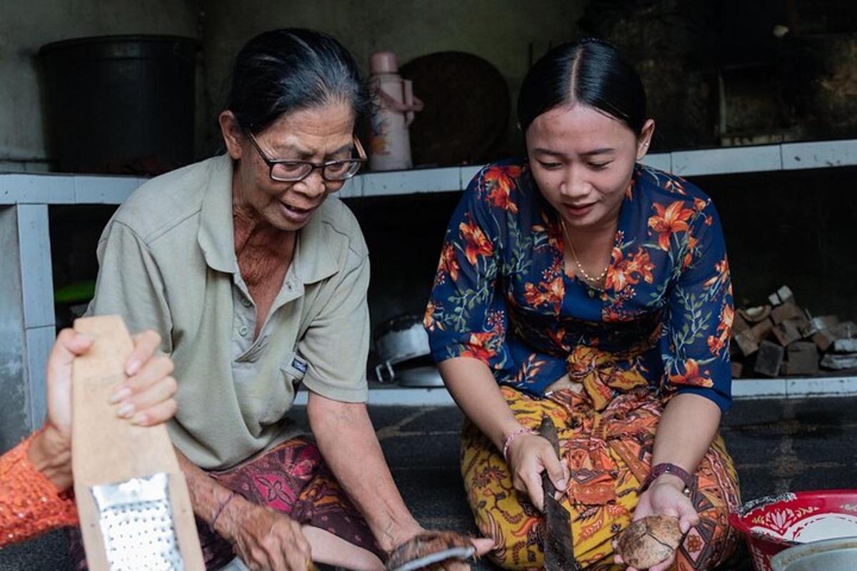 two women sitting on the ground looking at a persons leg