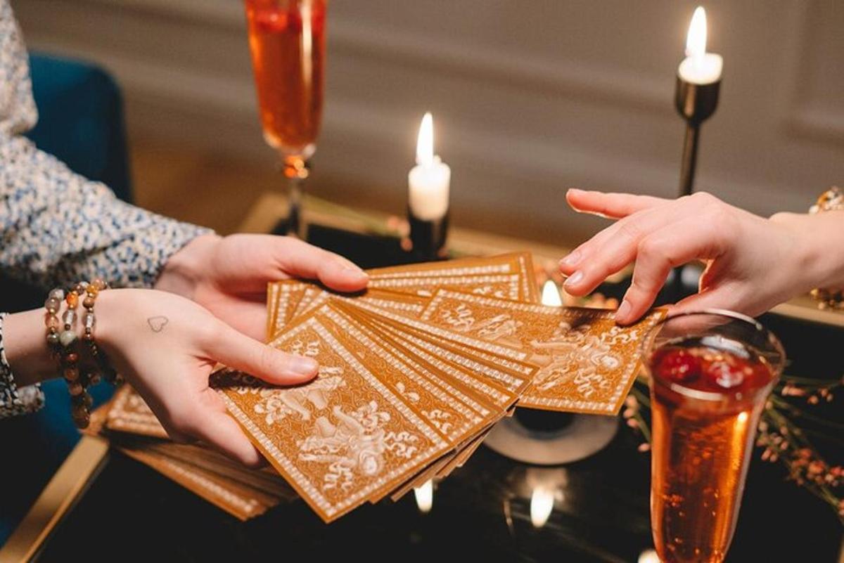 zwei Personen halten einen goldenen Geldbeutel auf einem Tisch mit Kerzen