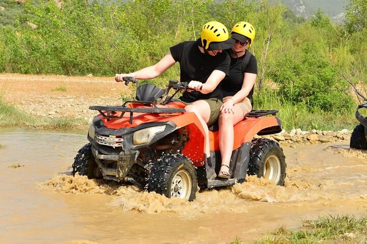 duas pessoas andando em um quadriciclo na lama