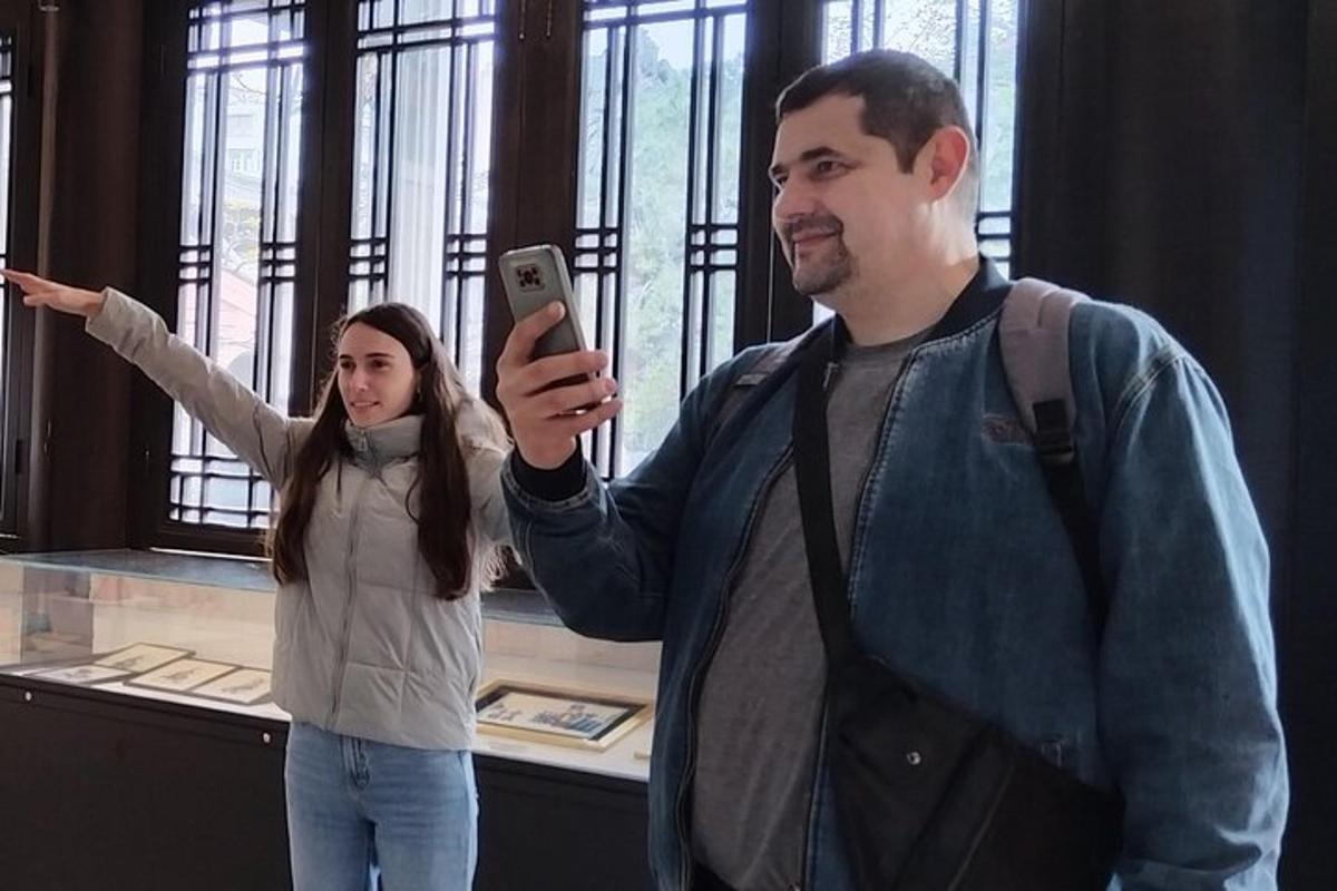 μια γυναίκα φωτογραφίζει έναν άντρα που κρατάει ένα κινητό τηλέφωνο