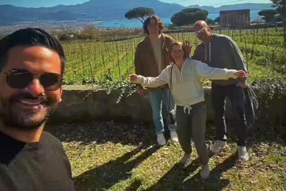 μια ομάδα ανθρώπων που περπατούν μέσα από έναν αμπελώνα