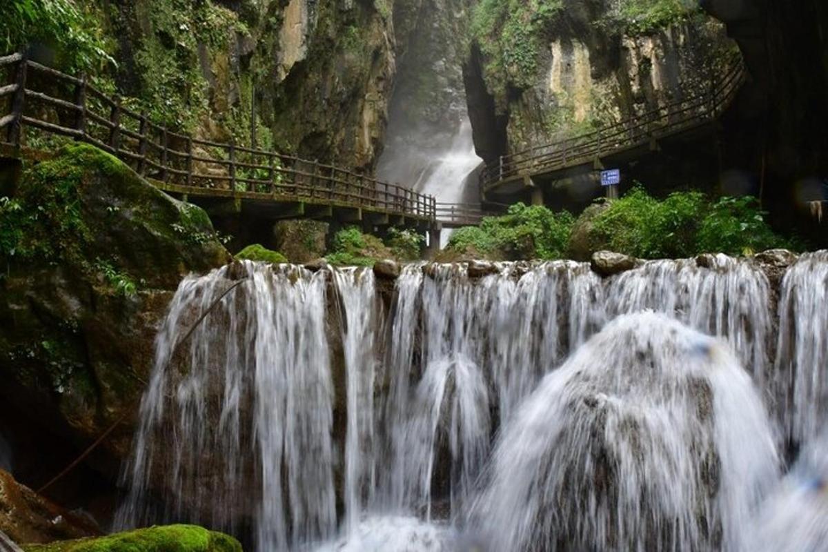 air terjun di hadapan gunung dengan jambatan