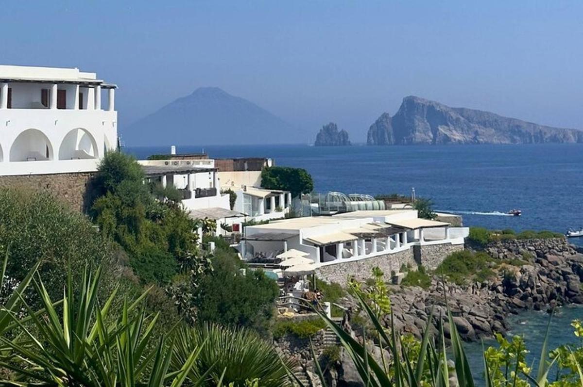 a white building on a hill next to the water