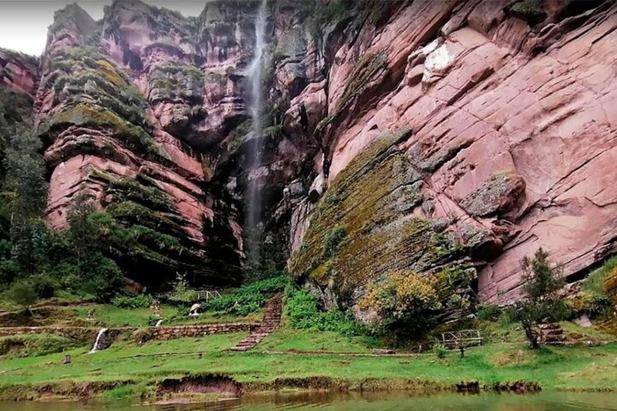 uma cachoeira em frente a uma montanha rochosa com um rio