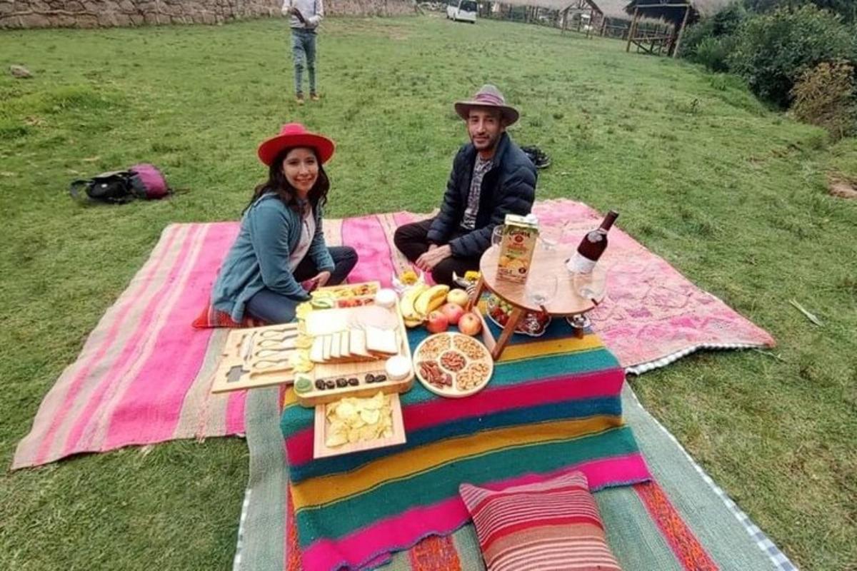 un bărbat și o femeie așezați la o pătură de picnic cu mâncare