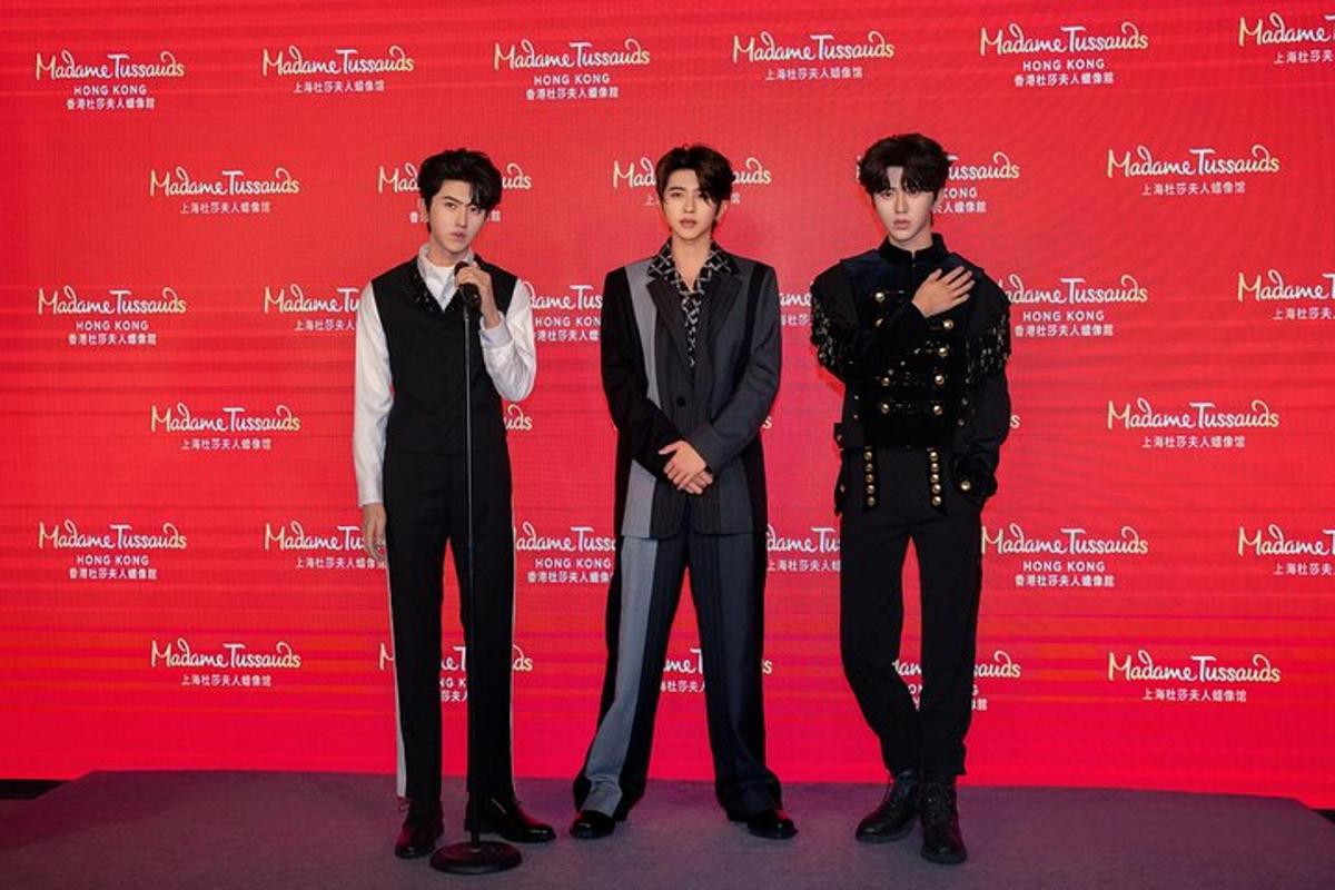 three young men standing in front of a red background