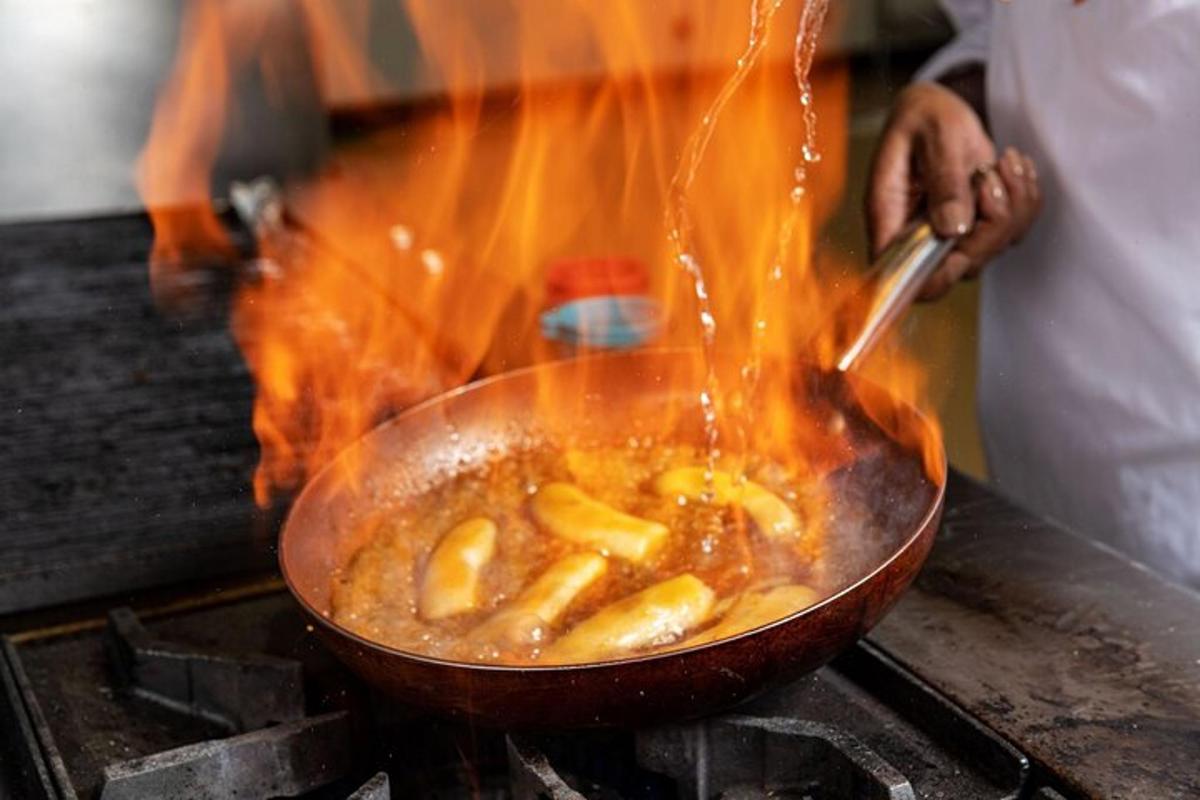 コンロの上の中華鍋で食べ物を調理している人