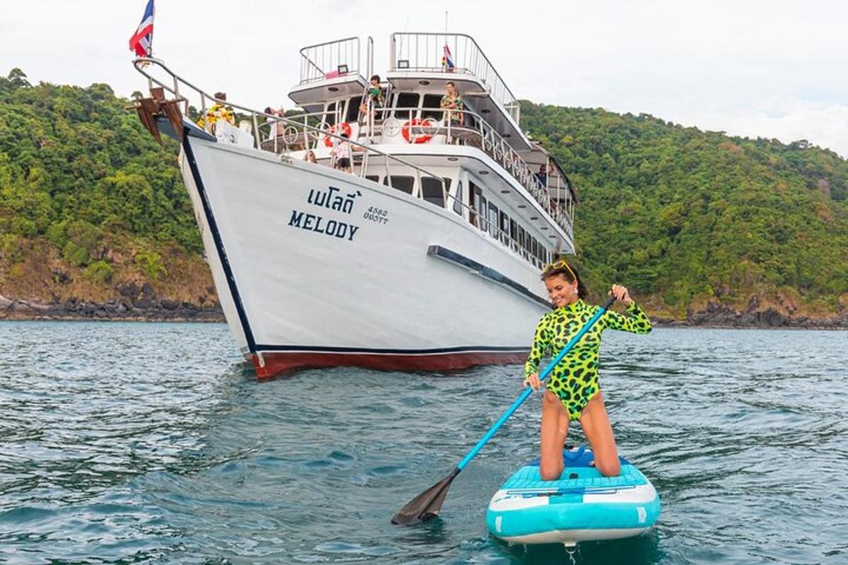 a young boy on a paddle board in front of a boat