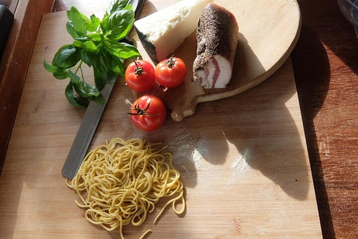 a cutting board with pasta and tomatoes and a knife