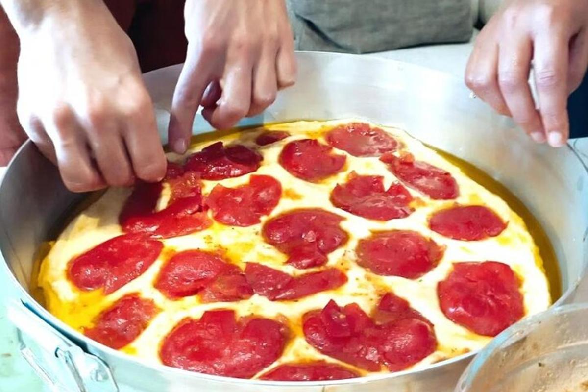 seseorang sedang membuat pizza pepperoni di wajan