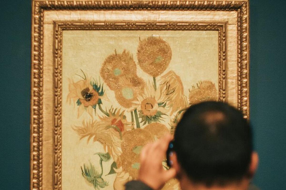 a man taking a picture of a painting of flowers