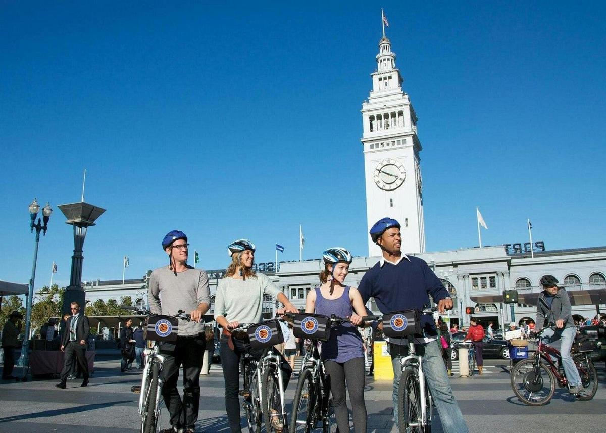 un grup de persones en bicicleta davant d'una torre del rellotge