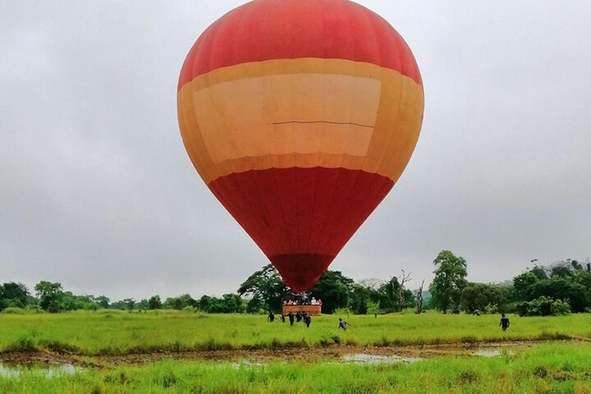 um balão de ar quente vermelho e amarelo em um campo