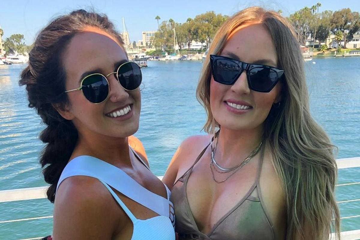 two women in bathing suits standing next to the water