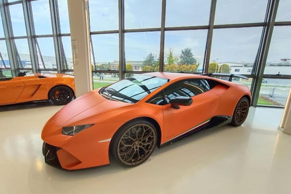 Dos coches naranjas estacionados en una habitación con ventanas.