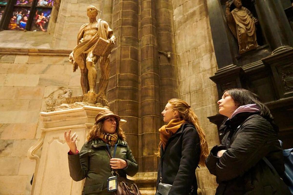 três mulheres em pé em frente a uma estátua em uma catedral