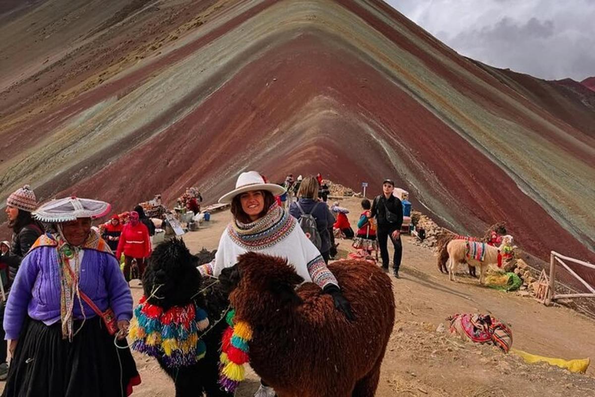 un gruppo di persone in piedi con animali e una montagna
