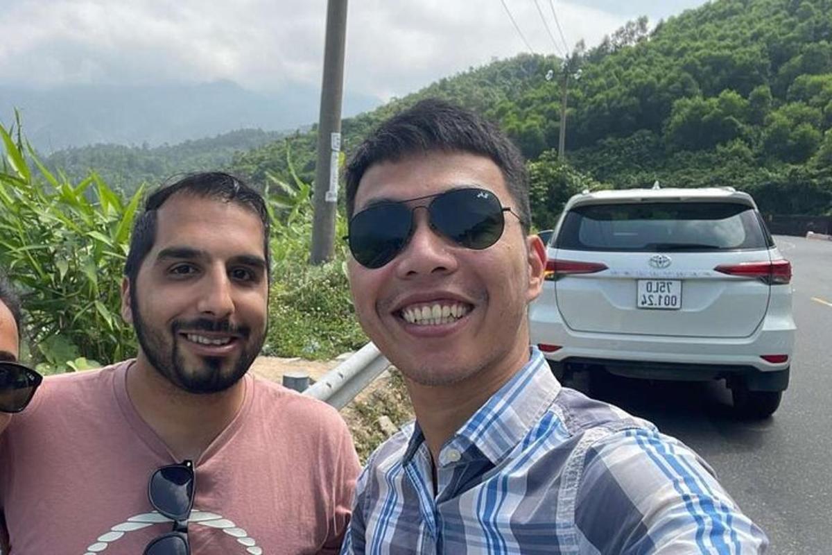 二人の男性が車の前で写真を撮っている