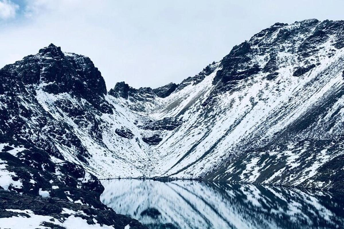 ein schneebedeckter Berg mit einer Spiegelung im Wasser