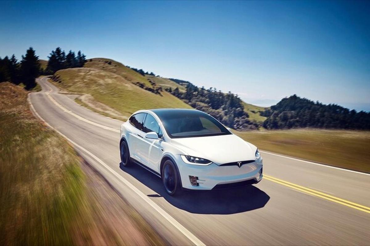 bílé auto Tesla jedoucí po silnici