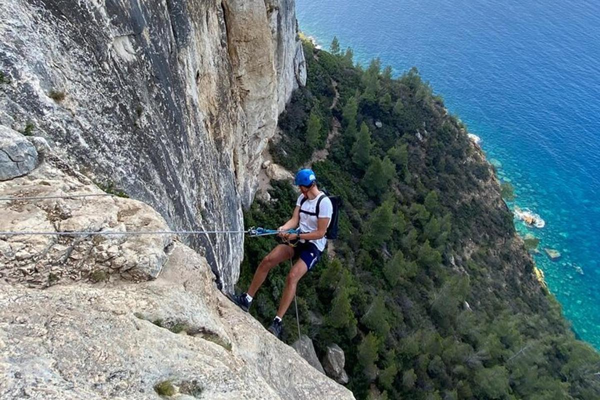 un homme debout sur une falaise tout en tenant une corde
