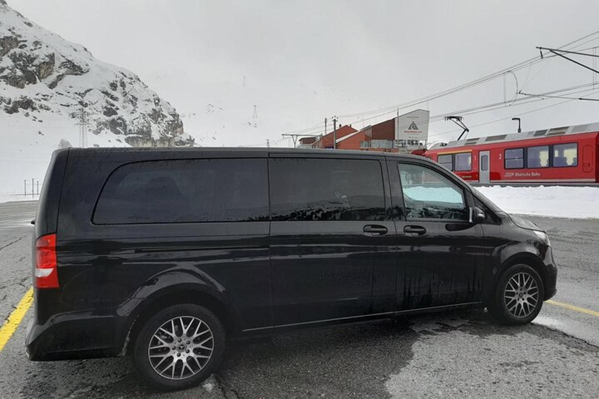 Černá dodávka zaparkovaná na parkovišti s vlakem